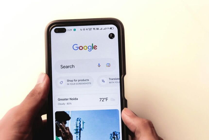 A close-up of a hand holding a smartphone with Google search displayed on the screen.