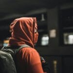 Portrait of an adult in a Spider-Man costume carrying a backpack in an urban subway station.