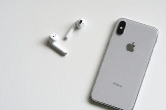 Close-up of a silver iPhone and wireless AirPods on a sleek white background.