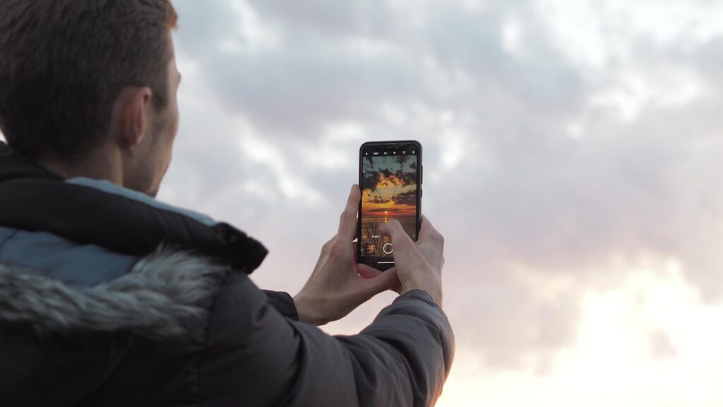 Chłopak robiący zdjęcie zachodu słońca smartfonem