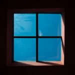 A window in a dark room with a blue sky