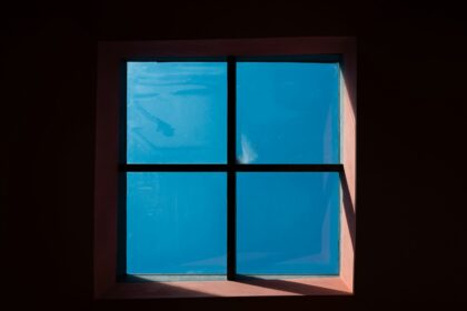 A window in a dark room with a blue sky
