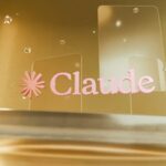 Pink "claude" logo on clear panels against a golden background